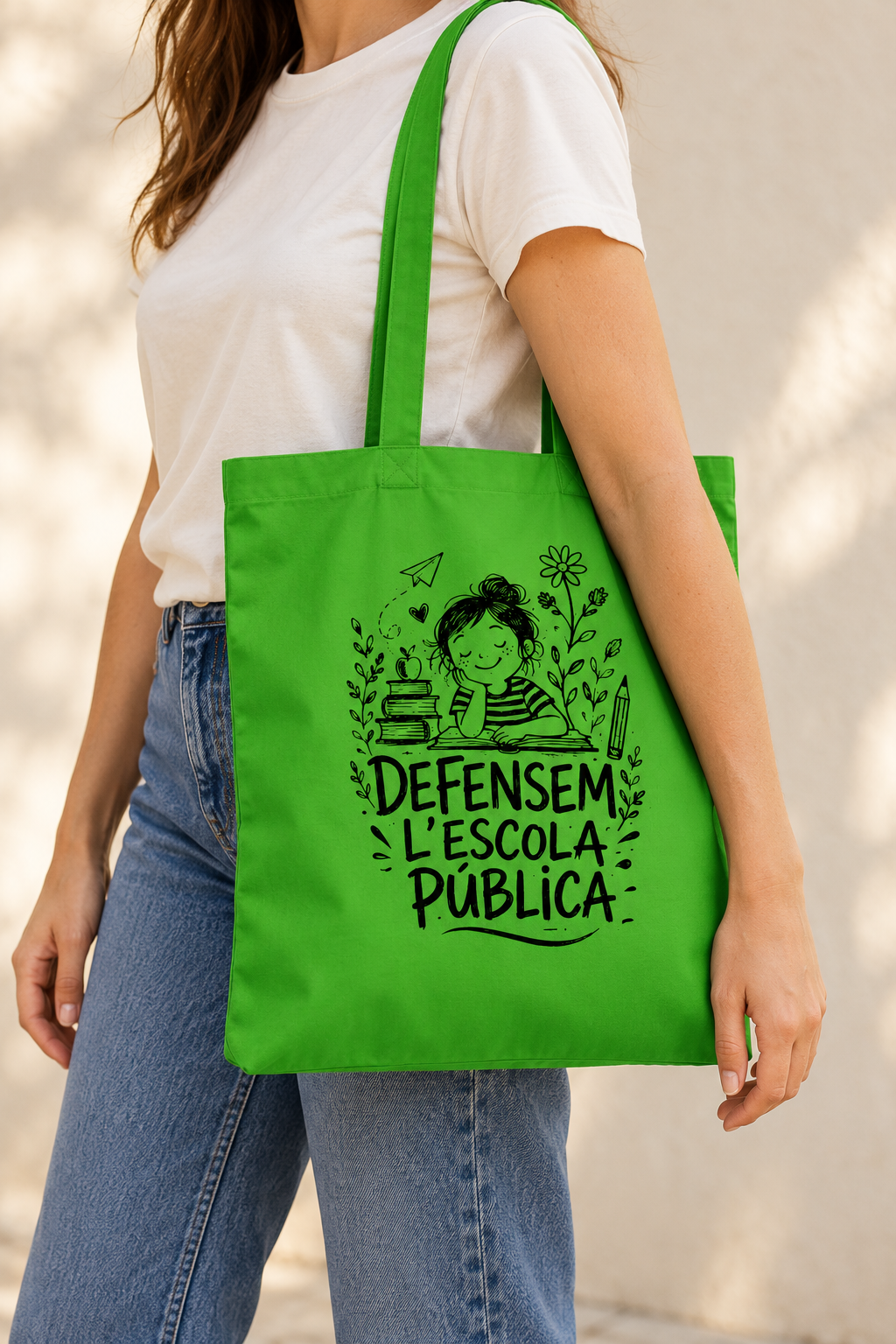 Tote bag verda «Defensem l'escola pública» portada a l'espatlla